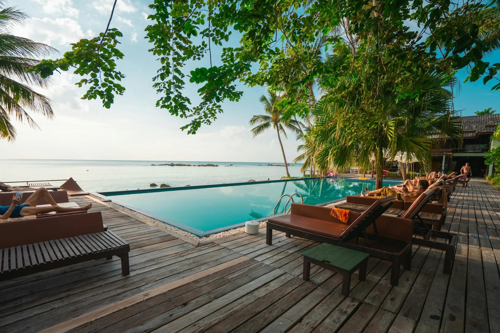 Pileta de un resort con reposeras y palmeras al atardecer